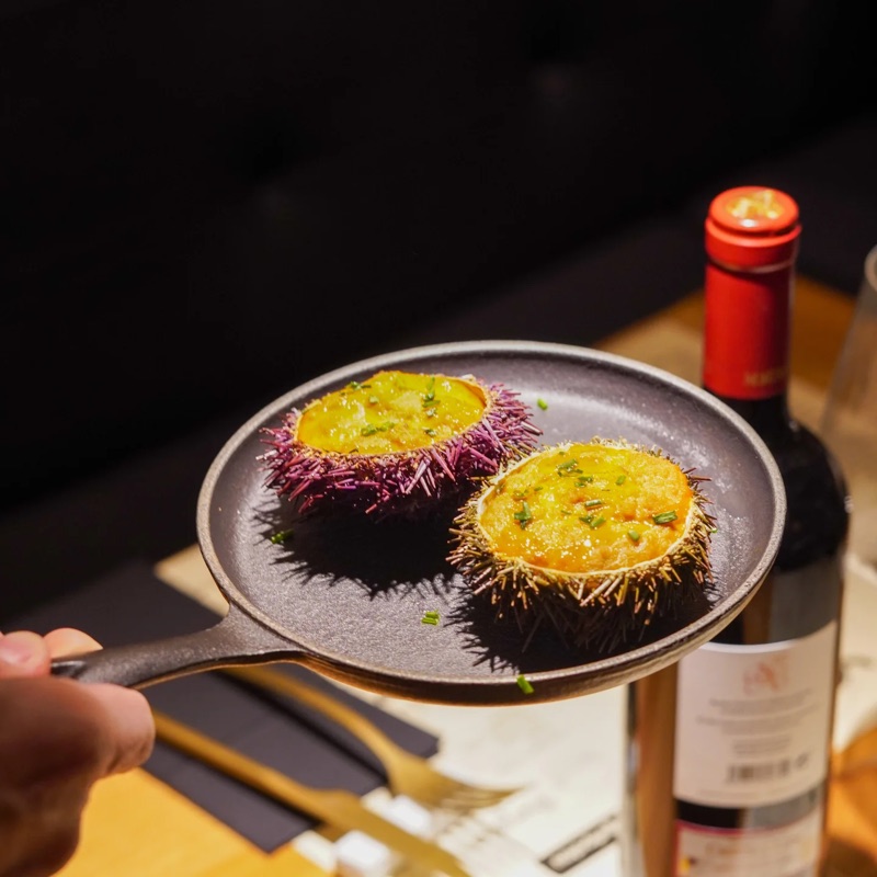 Dos eriçons de mar gratinats en una paella de ferro