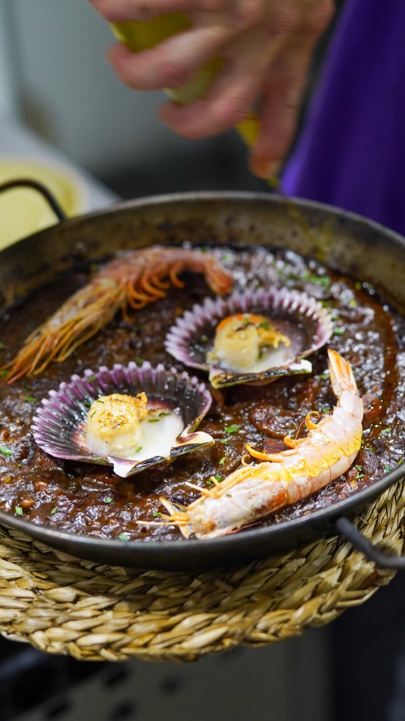 Algú serveix l’arròs amb gamba i petxines a la paella