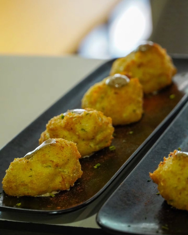 Croquetes amb salsa en una safata negra, vistes de costat