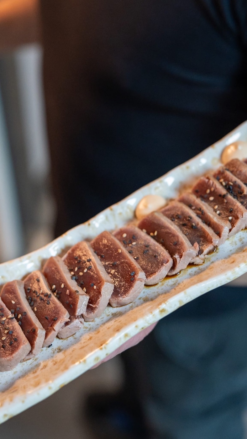 Una mà sosté una safata de tataki de tonyina