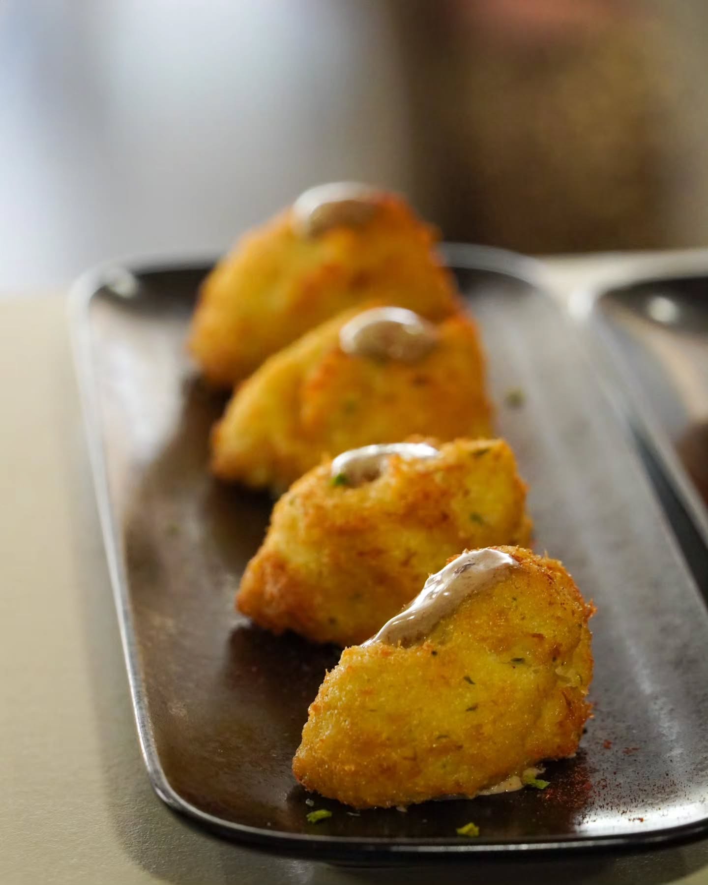 Croquetes amb un toc de salsa en una safata negra