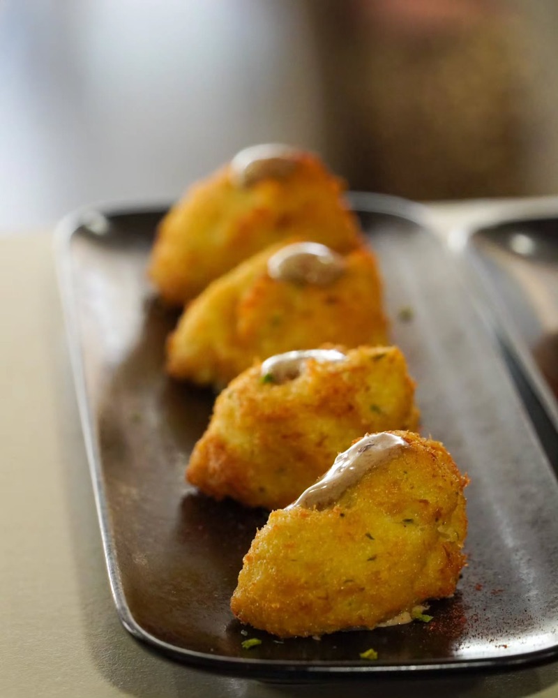 Croquetes amb un toc de salsa en una safata negra