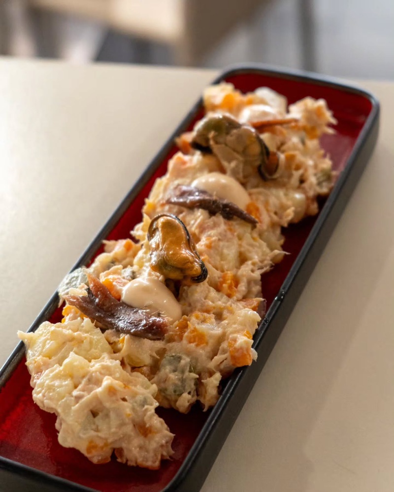 Ensaladilla amb musclos i anxoves en una safata vermella