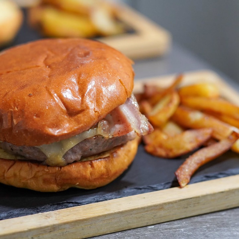 Hamburguesa amb formatge i patates fregides sobre una fusta