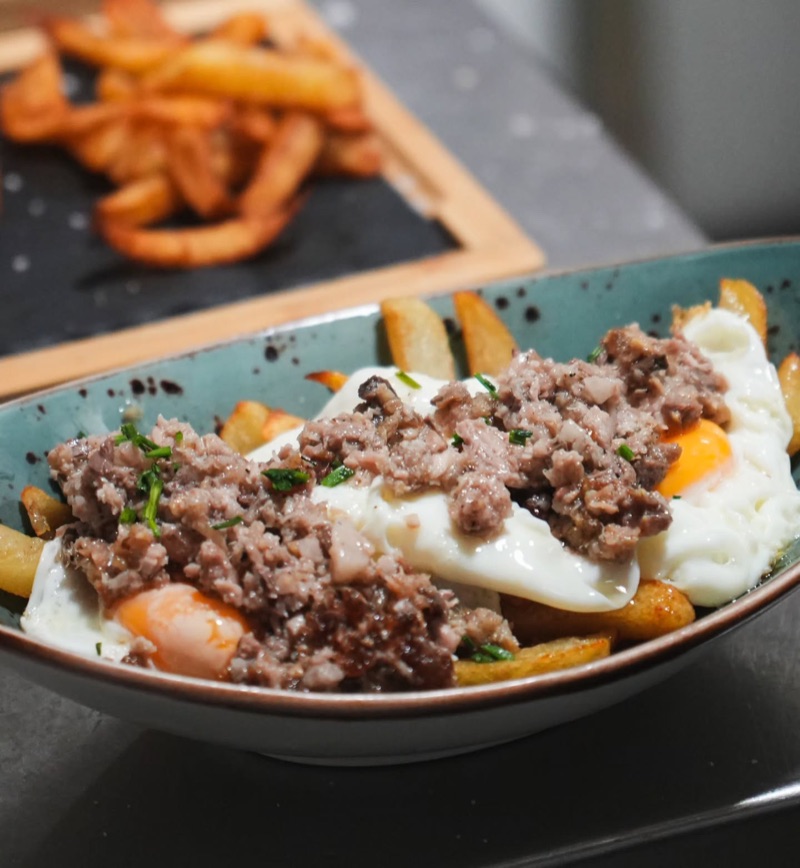 Ous trencats amb carn picada, amb patates fregides al darrere