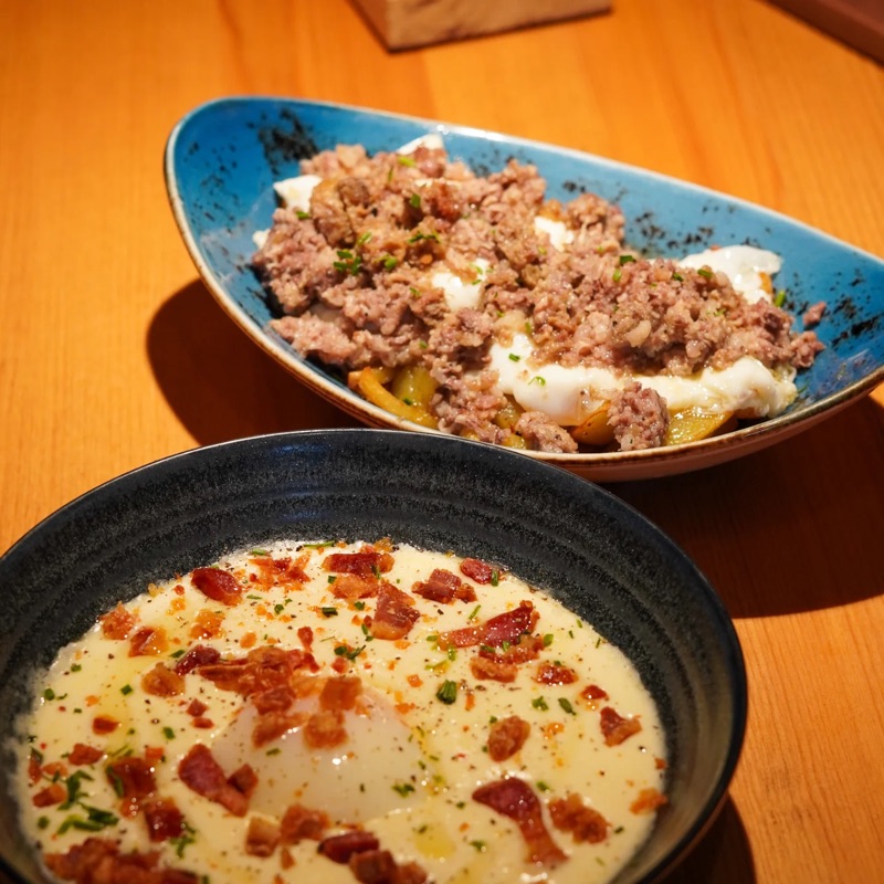 Ous trencats amb carn picada i un bol de crema amb daus de cansalada