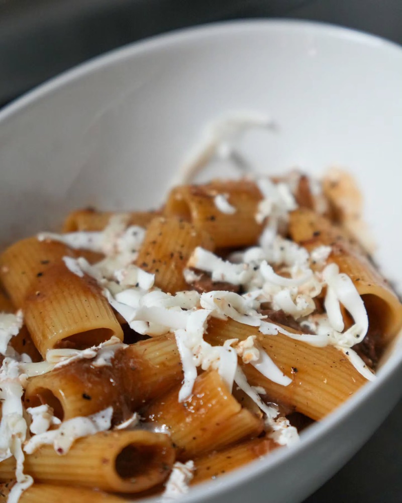 Rigatoni amb salsa i formatge ratllat en un bol blanc