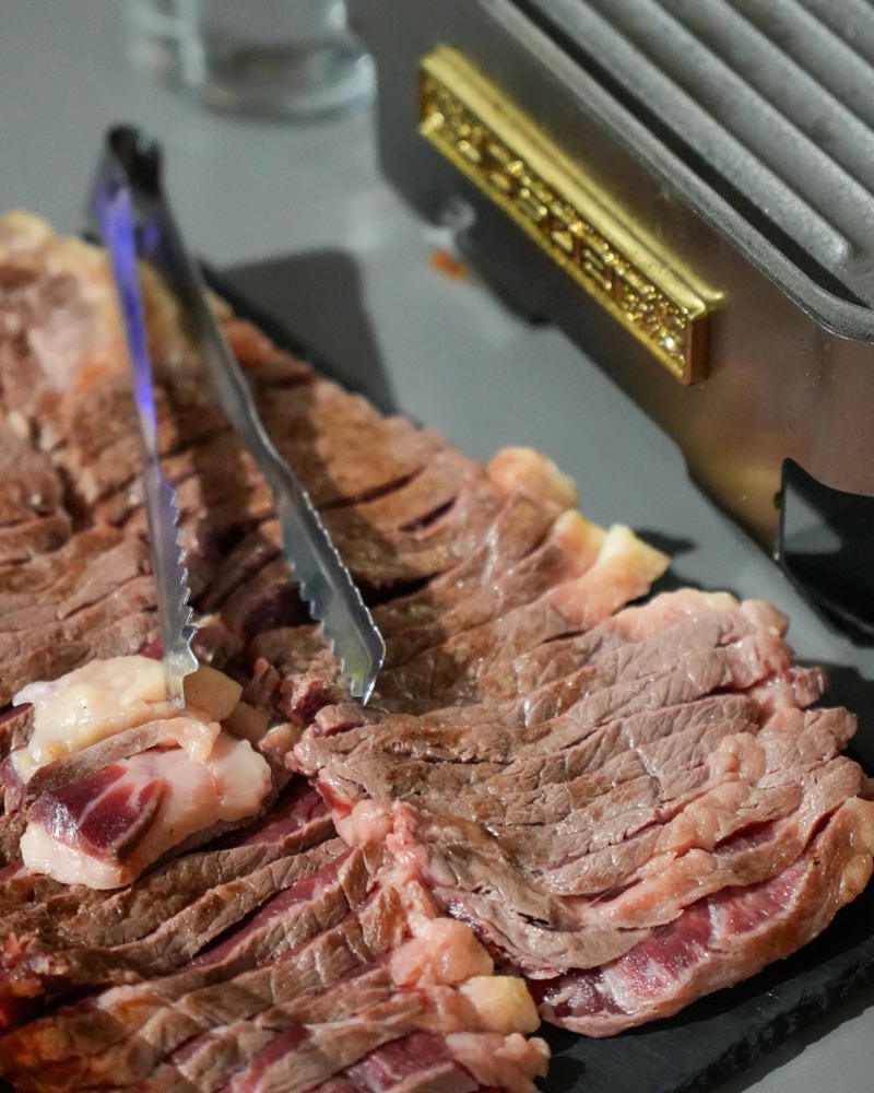 Chuletón filetejat sobre una pedra calenta, amb unes pinces