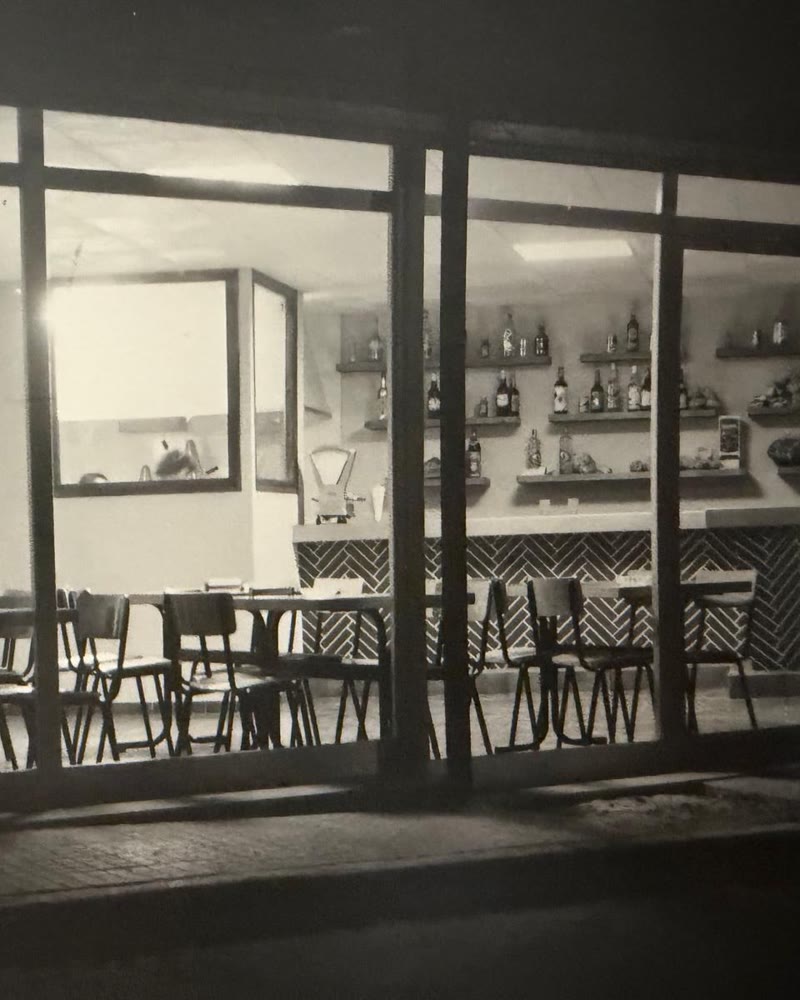 El Guti antic, de nit: la sala buida i la barra il·luminada darrere els vidres