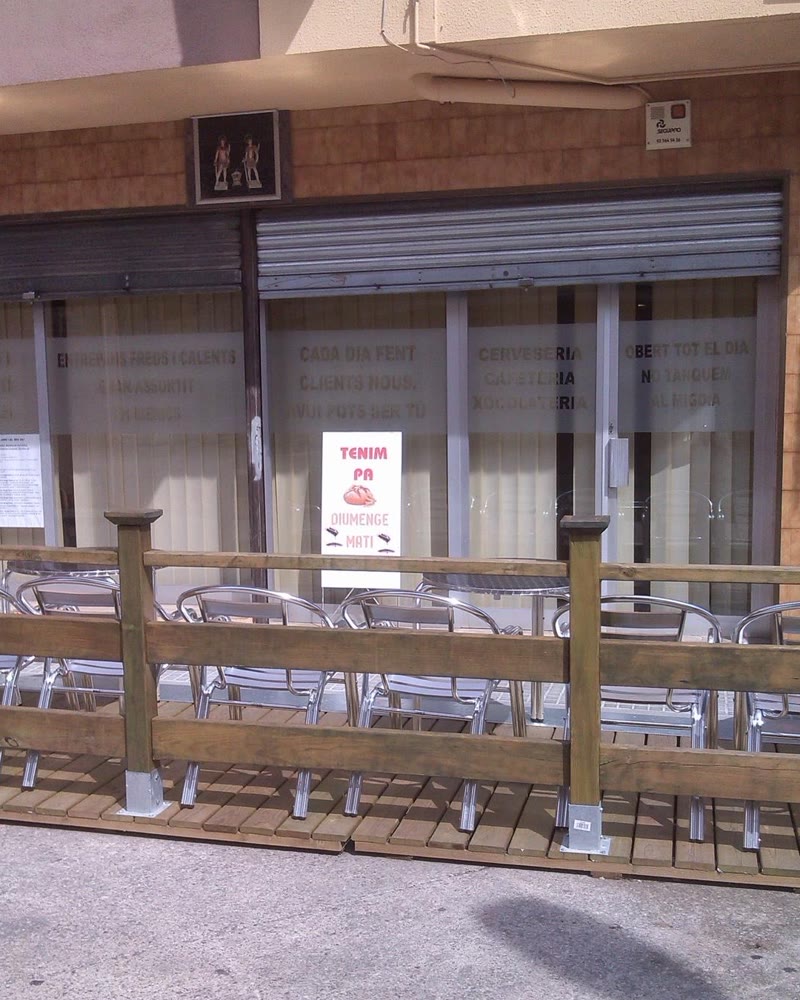 La terrassa de fusta davant dels vidres del Guti, amb cadires d’alumini