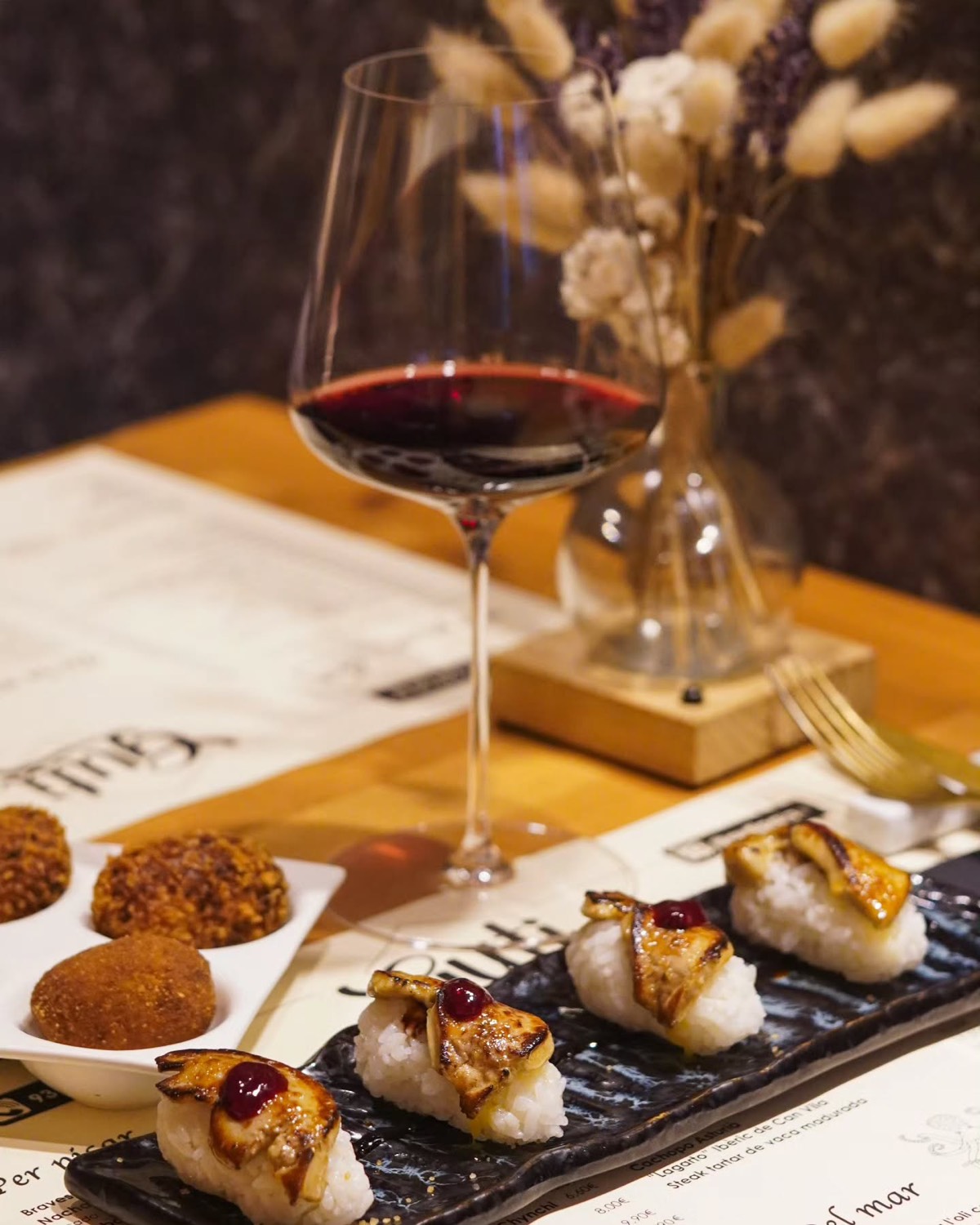 Nigiris de foie, croquetes i una copa de vi negre sobre les estovalles del Guti